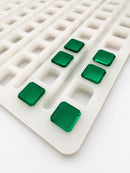 Angled view of a 2.3mL universal depositor cube gummy mold with 136 cavities and smooth emerald green cube gummies on a white background