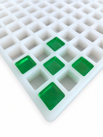 Close-up of a 2.625mL square gummy mold with 266 cavities showing translucent emerald green square gummies seated in the mold on a clean white background