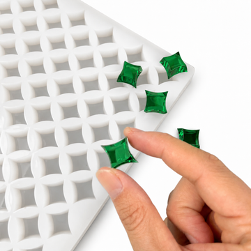Mano che preme una gummy verde smeraldo nello stampo a stella da 2 mL a 192 cavità