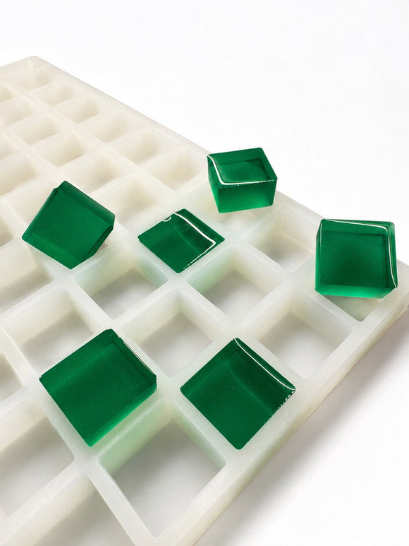 Stampo per caramelle gommose quadrate da 6 mL, 165 cavità — vista laterale angolata; gummies quadrate traslucide verde smeraldo; sfondo bianco